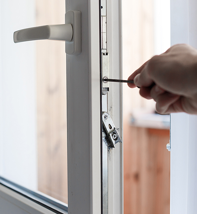 Person schraubt mit einem Schraubenzieher die Schrauben am Fenster nach